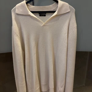 Vit kashmirtröja med krage från Massimo Dutti - Säljer en stilren vit tröja i mjuk kashmir från Massimo Dutti. Tröjan har lång ärm, klassisk krage och v-ringad hals. Perfekt för en clean och avslappnad look.