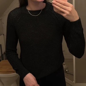 Svart stickad tröja från The Black Label Collection - Säljer en svart stickad tröja från The Black Label Collection i storlek S. Tröjan har rund halsringning, lång ärm och är tillverkad i en mjuk blandning av bomull och akryl. Perfekt basplagg för garderoben!