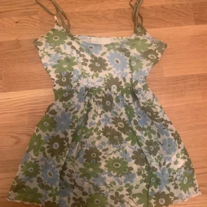 Blommigt sommar linne  - Söt topp med grönt och blått blommönster, smala axelband och knytband i midjan. Lätt och luftig modell, sitter super snyggt och går att justera baktill. Y2k 2000s vintige