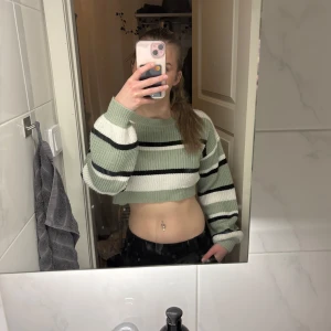 Grön och vit randig croppad tröja - Säljer en snygg croppad tröja i grönt och vitt med svarta ränder. Tröjan har långa ärmar och passar bra till både jeans och kjol!