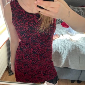 Svart och röd klänning med blommigt mönster - Snygg  klänning i svart och rött. Perfekt för en stilren look. 