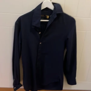 Mörkblå skjorta från Ralph Lauren - Snygg mörkblå skjorta från Ralph Lauren i slim fit. Skjortan har långa ärmar och knappar framtill. Perfekt för en stilren look.