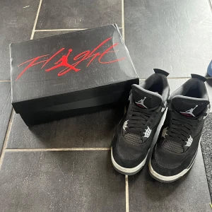 Svarta Nike Air Jordans 4 - SKICKAR SAMMA DAG ELLER DAGEN EFTER VID SNABB AFFÄR. Säljer ett par svarta Nike Air Jordans 4 med vita och grå detaljer. Skorna har klassisk siluett, snörning och rund tå. Kommer med originalkartong och har den ikoniska Jumpman-loggan på plösen.