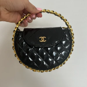 Svart mini väska i lack och guld detaljer  - Väskan är helt ny och inte använd kommer med dustbag. Säljs vid snabb affär. Skriv inte för att diskutera pris eller ställa självklara frågor 