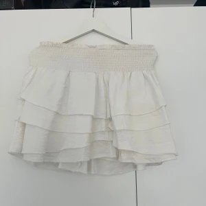 Vit volangkjol  - Säljer en söt vit volangkjol från Shein i storlek S. Kjolen har flera lager av volanger och en elastisk midja. Något kortare i modellen. Använt skick. 20kr
