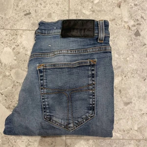 Tiger of sweden - Klassiska blå jeans med en bakficka och kontrastsömmar. Byxorna har en svart patch vid linningen och är i en rak modell. Perfekta till vardags för en avslappnad stil.
