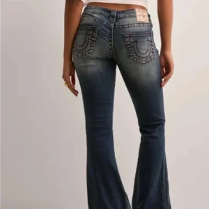 True Religion bootcut jeans blå (fri frakt på min profil!!!) - Säljer ett par blå low waist jeans från True Religion med bootcut passform. Jeansen har röda kontrastsömmar, klassiska bakfickor med broderad logga och silverfärgade knappar. Dom är sydda vid midjan men det går att sprätta bort. Storlek 28 vilket ungefär motsvaras storlek S/36. Nya pris är 1 299