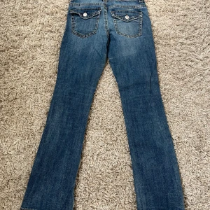 Blå bootcut jeans från Perfect Jeans - Snygga blå jeans från Perfect Jeans i klassisk bootcut-modell. Jeansen har bakfickor med lock och knapp, samt kontrastsömmar. Tillverkade i jeansmaterial med en något tvättad look. Perfekta för dig som gillar en tidlös stil. Det som ska tilläggas är att det är en reva på höger bakficka som gör att man ser lite igen när dom är på som visas på bilden men revan går abslout att laga för den som vill!