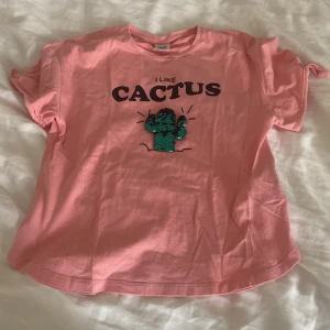 Rosa t-shirt med paljettkaktus Zara - Söt rosa t-shirt från Zara med texten 'I LIKE CACTUS' och en grön paljettkaktus på bröstet. Perfekt för dig som gillar färg och roliga detaljer.