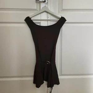 Brun kort offshoulder klänning med bälte! - Helt oanvänd brun kortklänning med offshoulder från bershka. Köpte klänningen för ett år sedan men var lite för liten, prislappen sitter kvar och allt. Orginal pris 399 kr. Klänningen säljs inte längre så passa på!!! Klänningen har ett coolt knytband med metallring i midjan och en lätt volangkant nedtill.❤️