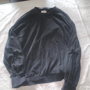 Svart långärmad sweatshirt med öppen rygg - Svart sweatshirt med rund hals och lång ärm. Baksidan har en cool öppen rygg-detalj som ger en unik look. Tröjan har breda muddar vid ärmslut och nederkant. Perfekt för dig som gillar stilrena plagg med en twist.