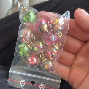 Färgglada fruktberlocker till smycken - Säljer ett set med 10 stycken runda berlocker i transparent plast med små färgglada fruktmotiv inuti, som kiwi, citron, jordgubb och drakfrukt. Perfekt att använda till halsband, armband eller örhängen. Berlockerna har guldfärgade fästen och är riktigt söta och unika.