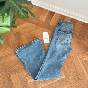 Lågmidjade jeans med fickor - Säljer ett par klassiska jeans i ljusblå denim. Modellen har bootcut-ben och femficksdesign med snygga sömmar. Perfekta för dig som gillar retrovibbar och en avslappnad look.