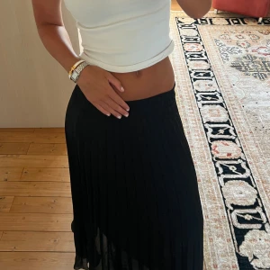Svart plisserad långkjol - Säljer en svart plisserad långkjol med flowy känsla och snygg midjeresår. Kjolen har ett skirt tyg som ger en cool och luftig vibe, perfekt för dig som gillar stilrena och enkla plagg. Passar dig som vill ha en klassisk look med edge.💛