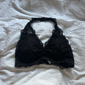 Svart spetsig bralette från Cubus - Supersnygg svart bralette i spets från Cubus med halterneck och fina spetsdetaljer runt kanterna. Perfekt att ha under en öppen skjorta eller som den är till ett par höga jeans. Mjuk och bekväm passform med tunna axelband.