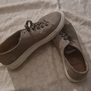 Beige mockasneakers från Les Deux - Snygga sneakers från Les Deux i beige mocka med rund tå och vit platt sula. Skorna är andvända bara ett fåtal gånger. Köpt för 1400 kr