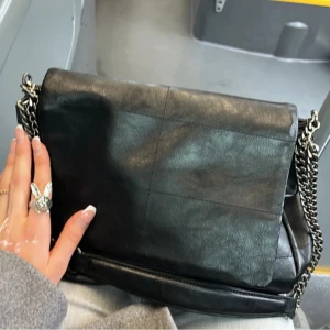 Svart axelväska med kedjedetalj - Svart väska ifrån Zara!! Väskan är i fin skick, enda defekten är att magneten som sitter på instiftan av locket för att tönta väskan har trillat av💗 skriv för fler bilder!