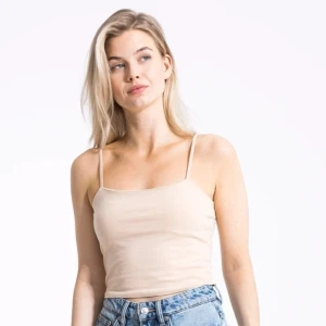 Beige linnetopp med smala axelband - Säljer en enkel och stilren beige linnetopp med smala axelband och rak halsringning. Toppen är croppad och gjord i mjuk bomull, perfekt till jeans eller kjol. Passformen är normal och toppen är ärmlös för en clean look.