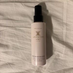 Antonio Axu Heat Protection Spray - Värmeskyddsspray från Antonio Axu i en stilren ljusrosa flaska med svart spraymunstycke. Perfekt för att skydda håret mot värmeskador vid styling. Lyxig design och enkel att använda.