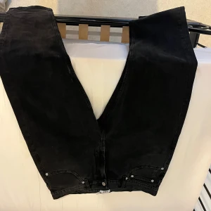 Svarta Levis 501 straight jeans - Klassiska svarta Levis 501 jeans med raka ben och femficksmodell. Jeansen har en normal passform och är tillverkade i robust denim. Perfekta för dig som gillar en tidlös och clean look. Snygga att matcha med sneakers eller boots.