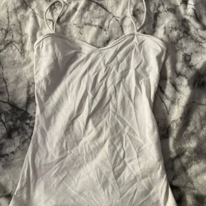 Vit linnetopp  - Enkel och stilren vit linnetopp från SHEIN i storlek XS. Toppen har tunna axelband och en rak, något figurnära passform. Perfekt att matcha med jeans eller kjol för en clean look. Materialet känns mjukt och lätt mot huden.