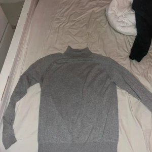 Grå polotröja från 157 Premium Basic - Snygg grå polotröja från 157 Premium Basic i storlek medium. Tröjan har ribbade muddar vid hals, ärmslut och nederkant, vilket ger en clean och stilren look. Perfekt att matcha med jeans eller dressade byxor för en chill vibe.