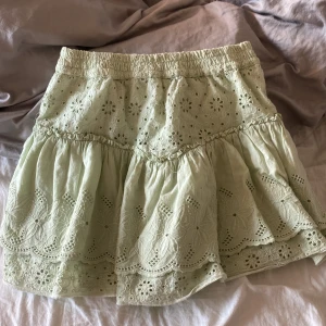 Ljusgrön broderad kjol från Zara - Kjolen har små röda prickar som visss på sista bilden men inget som syns vid användning🥰Supersöt ljusgrön kortkjol från Zara med broderade blommor och volangdetaljer. Kjolen har elastisk midja och är fodrad med shorts under, vilket gör den extra bekväm. Perfekt för vår och sommar när du vill ha en chill och feminin look.