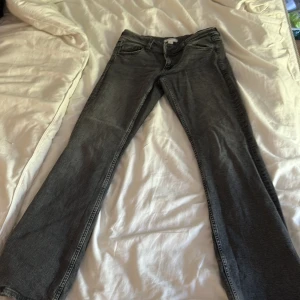 Gråa jeans från Gina Tricot - Säljer ett par mörkgråa jeans från Gina Tricot i storlek 170. Jeansen har klassisk femficksdesign, raka ben och snygg tvättad finish. Perfekta för dig som gillar en enkel och stilren look. Materialet är mjukt och följsamt jeans. De är lågmidjade . Jag som vanligtvis har 36 i jeansen kan ha detta utan problem .