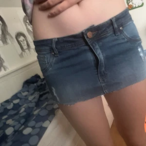 blå jeanskjol från YoungStyle - Säljer en snygg blå jeanskjol från YoungStyle. Kjolen är kort, har klassiska fickor fram och bak, rå kant nertill och coola slitningar för en trendig look. Perfekt till sneakers eller boots för en chill outfit.