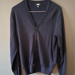 Mörkblå kofta från Uniqlo XS - Snygg mörkblå kofta från Uniqlo i storlek XS. Klassisk v-ringad modell med knappar framtill och långa ärmar. Tillverkad i mjuk bomull som känns skön mot huden. Perfekt att slänga över en t-shirt eller linne för en chill look. Ny pris 399