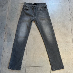 Replay grå jeans straight fit modell Wallys. - Snygga grå jeans från Replay med klassisk femficksdesign och raka ben. Jeansen har en cool tvättad look och svarta detaljer vid fickorna. Passar dig som gillar stilrena och tidlösa jeans med lite edge. Materialet är slitstarkt denim i bomull.