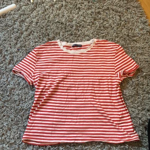Rödvit randig t-shirt från Zara - Snygg t-shirt från Zara i storlek S med röda och vita  ränder. Klassisk rund halsringning och korta ärmar. Mjuk och skön bomullskvalitet som är perfekt för varma dagar. Enkel och fräsch design som funkar till jeans eller shorts. Finns en ganska stor fläck på tröjan men den syns knappt. Nypris: vet ej