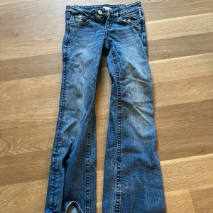 Blå bootcut jeans från Gina Tricot - Snygga blå jeans från Gina Tricot i storlek 152 med bootcut passform. Jeansen har coola detaljer med broderade bakfickor och silverknappar. Klassisk femficksmodell och låg midja. Perfekta för dig som gillar en avslappnad och trendig stil.