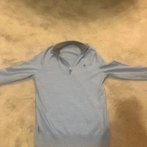 Ljusblå stickad half zip från Morris - Snygg ljusblå stickad tröja från Morris med half zip och liten broderad logga på bröstet. Merino ull och ganska liten i storleken passar S men är i M dock kan den passa folk som brukar ha på sig M så länge du inte är så bred axlad som mig.