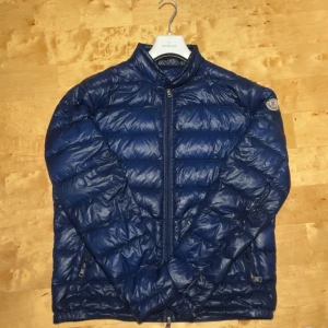 Blå dunjacka från Moncler - Snygg blå dunjacka från Moncler med quiltad design och dragkedja, Perfekt för kyliga dagar. Storlek 4 passar mig 175cm. Sönder bak till se sista bilden.