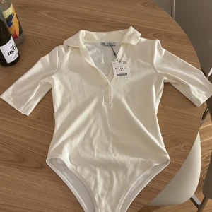 Polotshirt - Vit body med polokrage från Zara med knappar fram, endast provad. 🩷