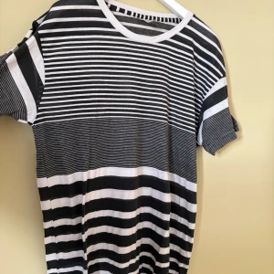 Randig t-shirt från American Apparel - Svartvit randig t-shirt från American Apparel med olika breda ränder över hela plagget. Klassisk rund hals och korta ärmar. T-shirten är i mjuk bomull och har en loose passform som ger en chill vibe.