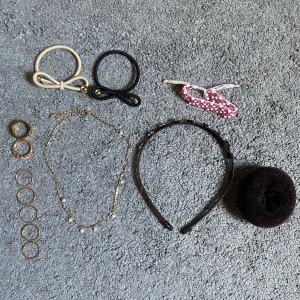 Mix av ringar, halsband och håraccessoarer - Säljer ett kit med flera guldfärgade ringar, ett tunt guldhalsband med små pärlor, samt ett svart diadem med glittriga stenar. Inkluderar även snoddar i beige, svart och rosa samt en hårdonut. Edblad ring storlek 18,50.