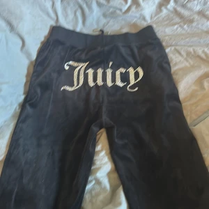 Svarta Juicy Couture mjukisbyxor - Svarta mjukisbyxor från Juicy Couture i mjuk velour med snörning i midjan och fickor. Baksidan har stora glittriga strassbokstäver med texten 'Juicy'.  Inte använt så många gånger