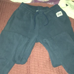 Mörkblå mjukisbyxor Andy S - Mörkblå mjukisbyxor från Andy by Frank Dandy i storlek S. Byxorna har resår i midjan med snörning och en mjuk, skön bomullskänsla. Perfekta för chill eller träning. Diskret logga på höften och klassisk loose passform.