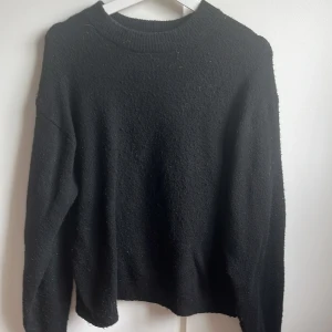 Svart stickad tröja med rund hals - En enkel svart stickad tröja med rundad hals och långa ärmar. Mjuk och lite fluffig känsla i materialet, perfekt för kyliga dagar. Passar dig som gillar en klassisk och clean look.