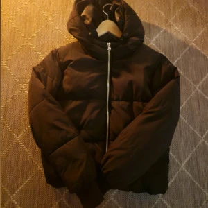 Svart pufferjacka med huva - Svart pufferjacka med huva och silverfärgad dragkedja framtill. Jackan är lite cropped så den funkar mer i början av hösten eller våren mer 