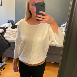 Vit croppad tröja med rund hals - Säljer en vit croppad tröja med rundad hals och trekvartsärm. Tröjan har en loose passform och är tillverkad i mjukt material som känns skönt mot huden. Perfekt för dig som gillar enkel och clean stil.