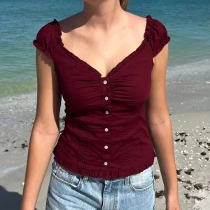 Vinröd blus  - Säljer en helt ny vinröd blus 100% bomull från Brandy Melville! Toppen va tyvärr för stor och vill prova sälja så slipper jag frakta tillbaks till USA🩵🩵XS/S (obs bilderna är från Brandys hemsida)