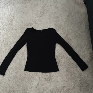 Svart långärmad topp från SHEIN - Svart långärmad topp från SHEIN i storlek S. Enkel och stilren design med rund halsringning och figurnära passform. Perfekt att matcha med jeans eller kjol för en clean look. Materialet känns mjukt och stretchigt, vilket gör den skön att bära hela dagen.