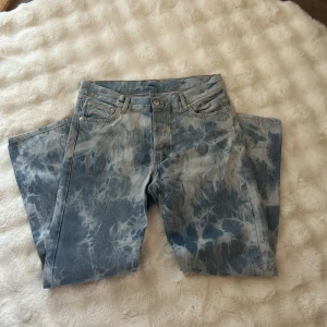 Sweet sktbs loose jeans batik blå - Säljer ett par loose fit jeans från Sweet sktbs i storlek 31. De är ljusblå med batikmönster och har klassisk femficksdesign. Materialet är 100% bomull och modellen heter Sweet Loose Jeans. Perfekt för dig som gillar streetwear och unik stil.