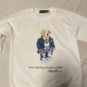 Vit Polo Bear tröja från Ralph Lauren - Vit långärmad tröja från Ralph Lauren med trycket Polo bear på framsidan. Tröjan har rund halsringning och är gjord i mjuk bomull. Säljer pågrund av att den är liten. Aldrig använd bara testad.