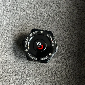 Vit Casio G-Shock digital klocka - Säljer en stilren vit Casio G-Shock digital klocka med fyrkantig display och robust design. Klockan har tydliga svarta detaljer och kommer i en svart sexkantig box. Perfekt för dig som gillar sportig och modern stil.