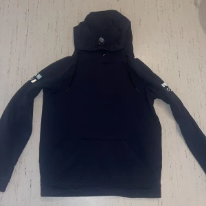 Mörkblå hoodie från Sail Racing - Mörkblå hoodie från Sail Racing med huva och snörning. Har haft ett tag men börjat bli liten men i bra skick.