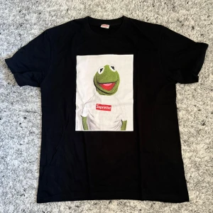 Supreme Tröja – Kermit the Frog (Svart) - Supreme Tröja – Kermit the Frog (Svart) 👕 Storlek: M 🔄 Skick: 9/10 – mycket fint skick, sparsamt använd 🖤 Färg: Svart 🐸 Design: Supreme x Kermit the Frog 